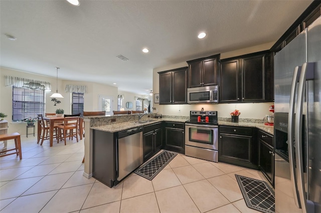 kitchen featuring light tile patterned floors, kitchen peninsula, stainless steel appliances, and hanging light fixtures