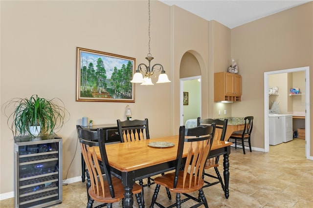 dining room with a chandelier, a towering ceiling, wine cooler, and washing machine and dryer