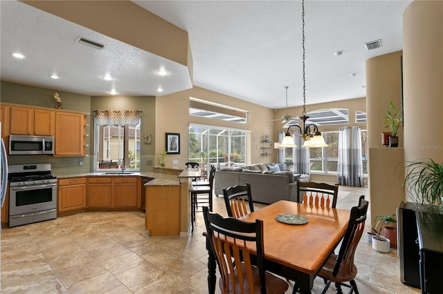 dining space with a textured ceiling, sink, and an inviting chandelier