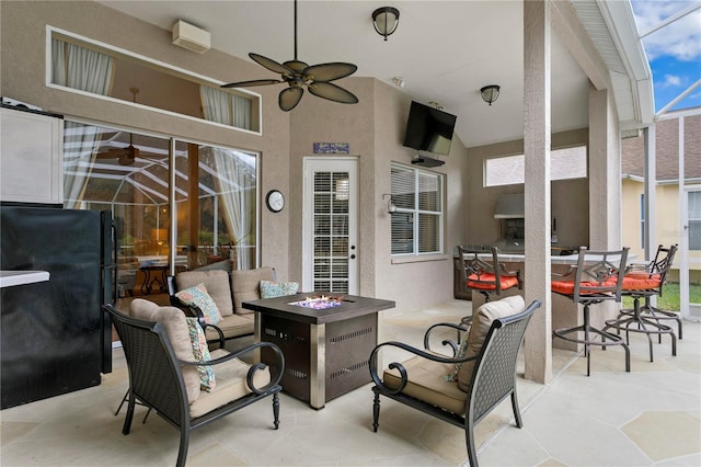 view of patio / terrace featuring glass enclosure, ceiling fan, and an outdoor living space with a fire pit