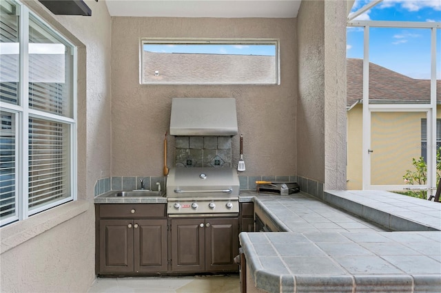 view of patio with sink, glass enclosure, area for grilling, and exterior kitchen