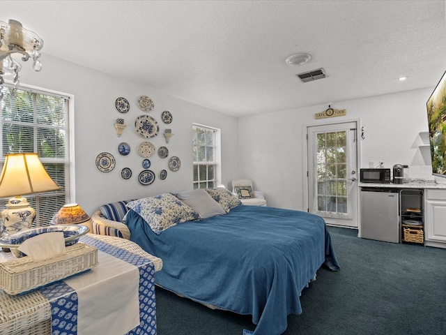 bedroom featuring dark colored carpet, stainless steel fridge, access to outside, and multiple windows