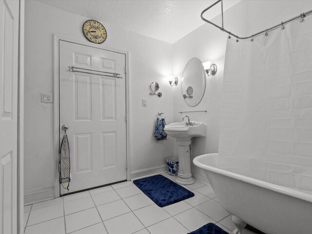 bathroom featuring a textured ceiling, plus walk in shower, and tile patterned flooring