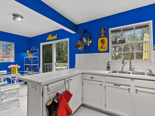 kitchen featuring plenty of natural light, sink, white cabinets, and kitchen peninsula