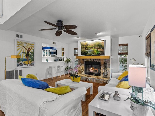 living room with ceiling fan, a fireplace, and hardwood / wood-style flooring