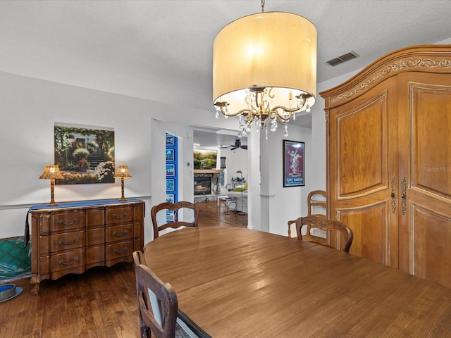 dining space with ceiling fan with notable chandelier and dark hardwood / wood-style floors