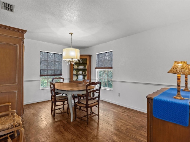 dining space featuring a wealth of natural light, dark hardwood / wood-style flooring, a textured ceiling, and a chandelier