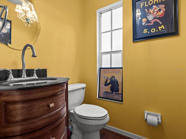 bathroom featuring hardwood / wood-style flooring, toilet, vanity, and a chandelier