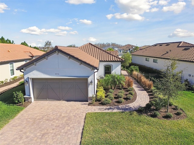 mediterranean / spanish home featuring a garage and a front lawn