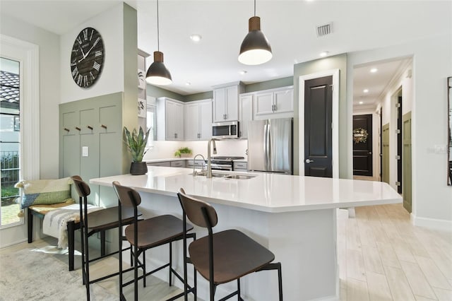 kitchen featuring a breakfast bar, sink, hanging light fixtures, white cabinetry, and stainless steel appliances