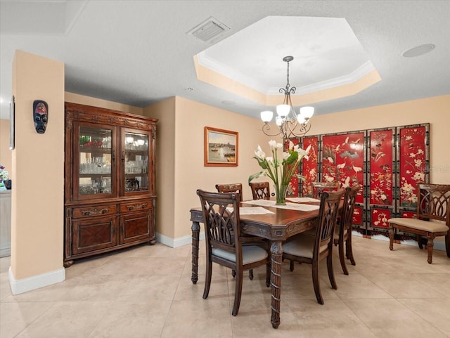 tiled dining room featuring ornamental molding, a tray ceiling, and a notable chandelier