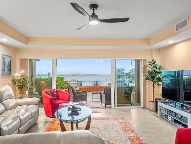 tiled living room with a raised ceiling and ceiling fan