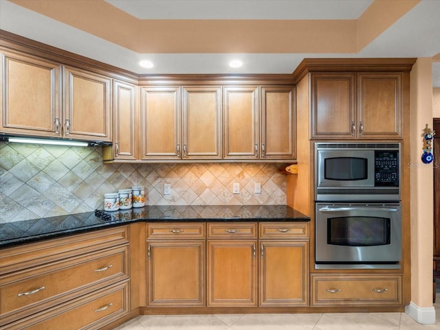 kitchen featuring appliances with stainless steel finishes, dark stone countertops, and light tile patterned floors