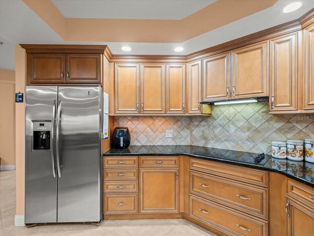 kitchen featuring stainless steel fridge with ice dispenser, black electric stovetop, dark stone countertops, and light tile patterned floors