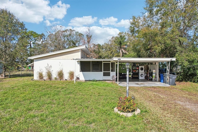 rear view of property featuring a carport, a sunroom, and a lawn