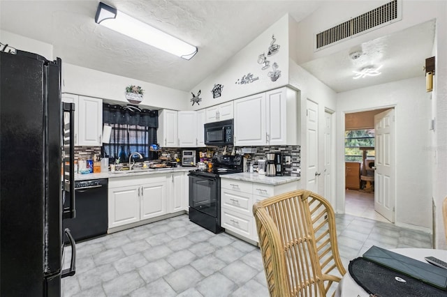 kitchen with sink, tasteful backsplash, black appliances, vaulted ceiling, and white cabinets