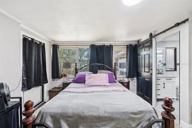 bedroom featuring ornamental molding, a barn door, and a textured ceiling