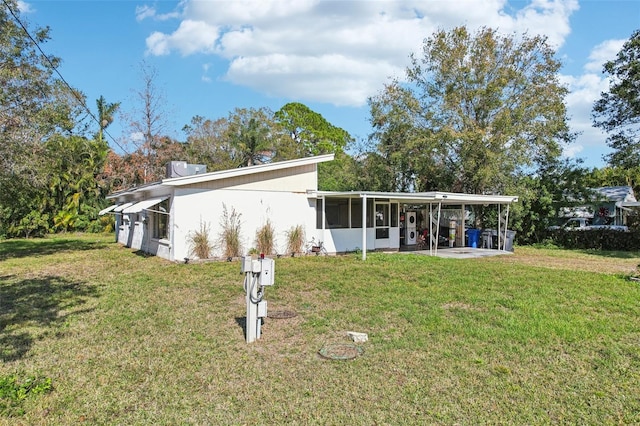 back of house featuring a lawn and a sunroom