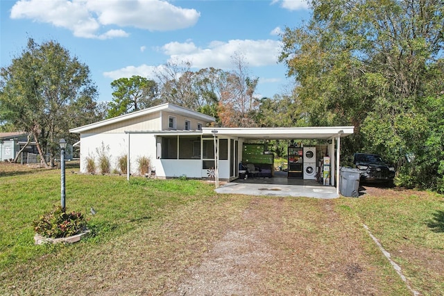 back of property featuring a carport, a sunroom, and a lawn