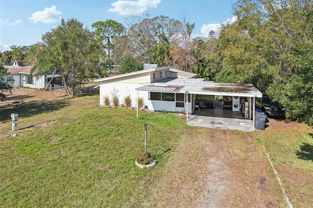 back of property with a lawn and a carport