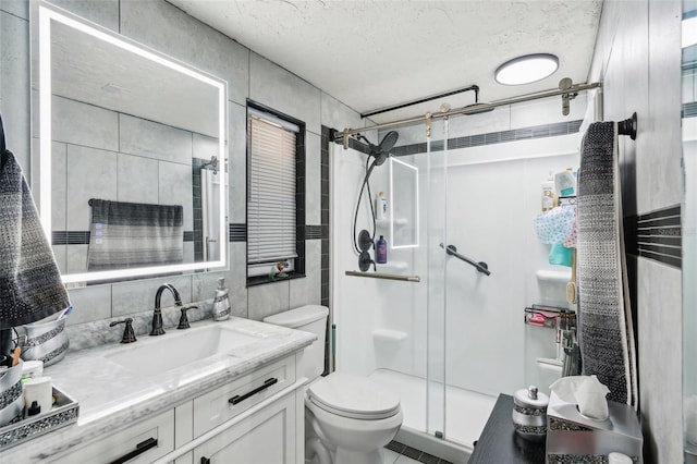 bathroom featuring tile walls, vanity, an enclosed shower, a textured ceiling, and toilet