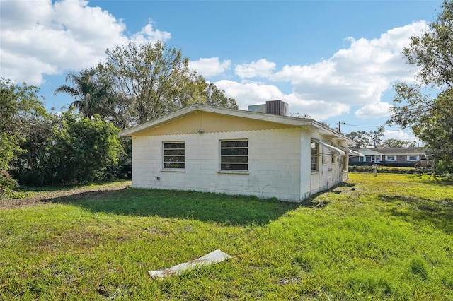 view of side of property featuring central AC and a lawn