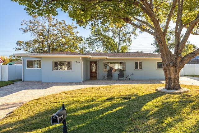 ranch-style home featuring a front lawn and a patio