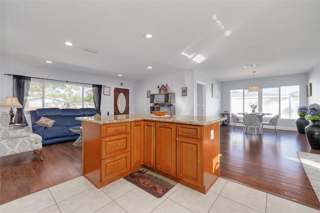 kitchen with a healthy amount of sunlight, a center island, light tile patterned floors, and hanging light fixtures