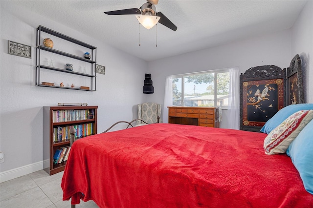 bedroom featuring ceiling fan, light tile patterned floors, and a textured ceiling