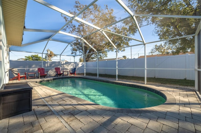 view of swimming pool featuring glass enclosure and a patio