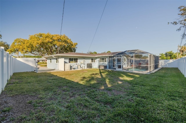 back of house with a lawn, a lanai, and a fenced in pool