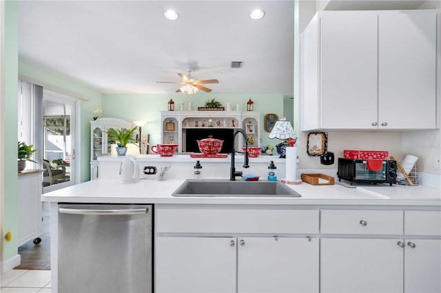 kitchen featuring kitchen peninsula, stainless steel dishwasher, sink, white cabinets, and light tile patterned flooring