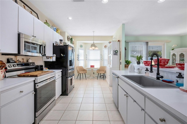 kitchen featuring white cabinetry, sink, decorative light fixtures, light tile patterned flooring, and appliances with stainless steel finishes