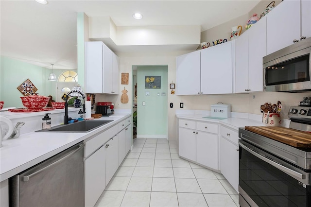 kitchen with sink, white cabinets, light tile patterned floors, and appliances with stainless steel finishes