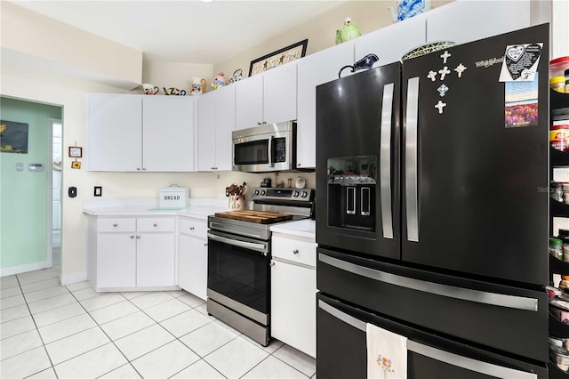 kitchen with light tile patterned flooring, white cabinets, and stainless steel appliances