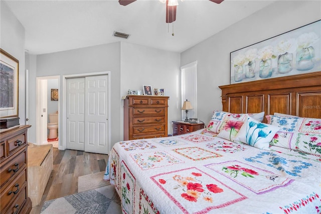 bedroom with light wood-type flooring, ensuite bathroom, a closet, and ceiling fan