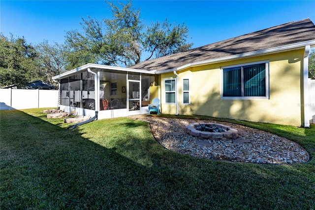 back of house featuring an outdoor fire pit, a lawn, and a sunroom