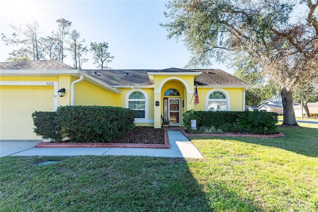 5215 New Brittany Ln, Zephyrhills, FL 33541 - view of front of property with an attached garage, stucco siding, a front lawn, and a shingled roof