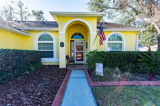 5215 New Brittany Ln, Zephyrhills, FL 33541 - doorway to property with stucco siding and a shingled roof