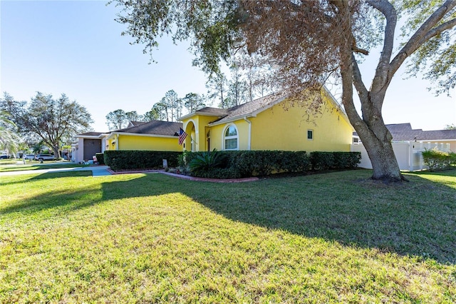 5215 New Brittany Ln, Zephyrhills, FL 33541 - view of property exterior with stucco siding, a lawn, and a garage