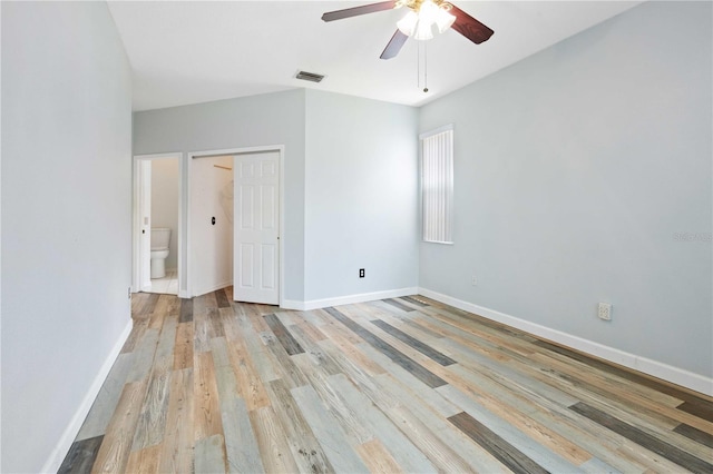 5215 New Brittany Ln, Zephyrhills, FL 33541 - unfurnished bedroom with light wood finished floors, baseboards, connected bathroom, ceiling fan, and a closet