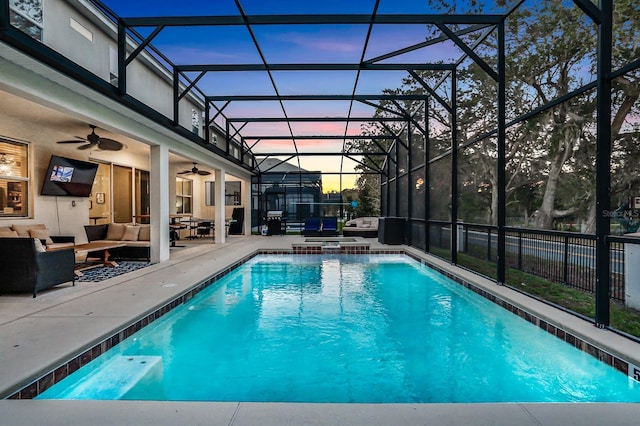 pool at dusk with glass enclosure, ceiling fan, an outdoor living space, a patio area, and an in ground hot tub