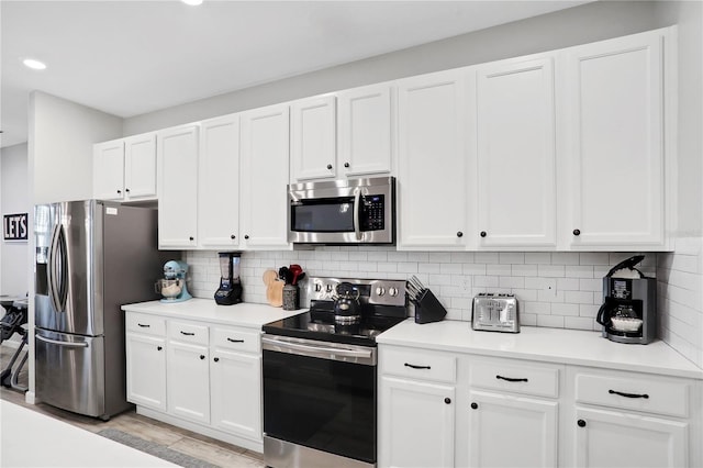 kitchen featuring stainless steel appliances, white cabinetry, tasteful backsplash, and light hardwood / wood-style floors