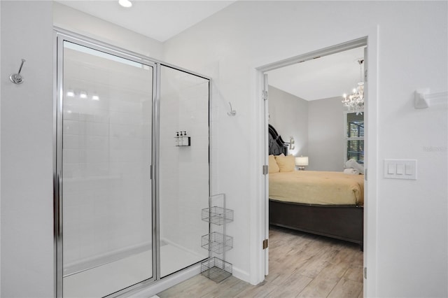 bathroom with a chandelier, wood-type flooring, and a shower with shower door