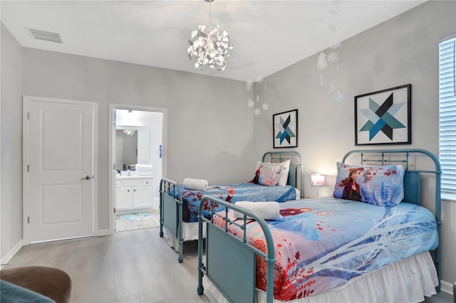 bedroom with light hardwood / wood-style flooring, connected bathroom, and an inviting chandelier