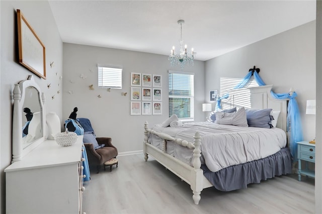 bedroom featuring a notable chandelier, light hardwood / wood-style floors, and multiple windows