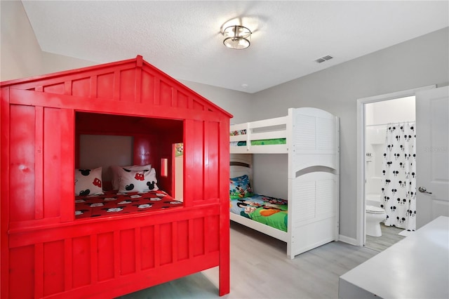 bedroom with ensuite bath and hardwood / wood-style floors