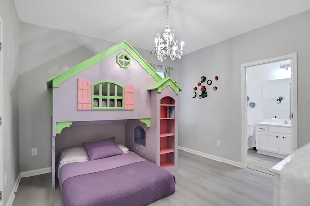 bedroom featuring light wood-type flooring, ensuite bathroom, a notable chandelier, and sink