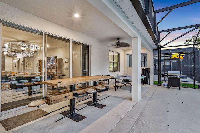 patio terrace at dusk featuring ceiling fan and a lanai