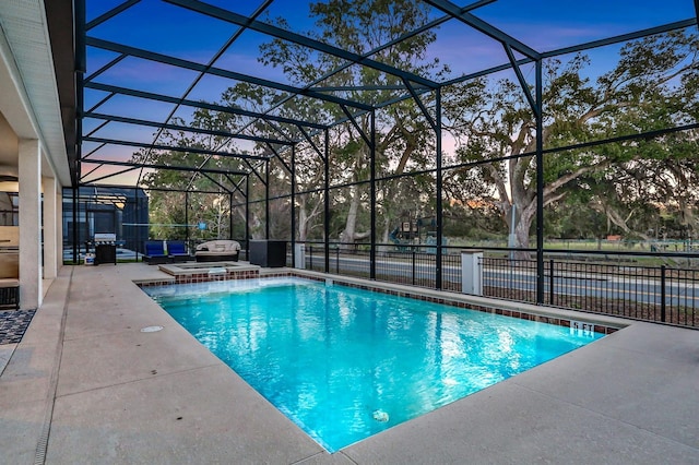 pool at dusk featuring a patio area and a lanai